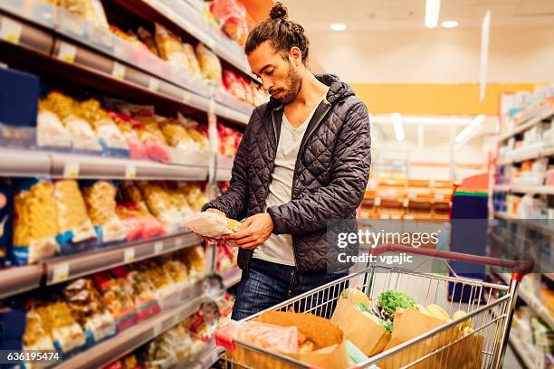 young bearded man in a supermarket. - nutrition label stock pictures, royalty-free photos & images