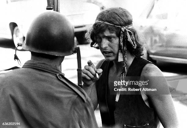 Man smokes a cigarette as he talks to an armored guard at People's Park circa May, 1969 in Berkeley, California.