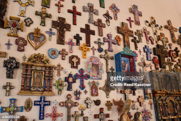 religious articles line a wall in a shop in todos santos,mexico. - todos santos stockfoto's en -beelden