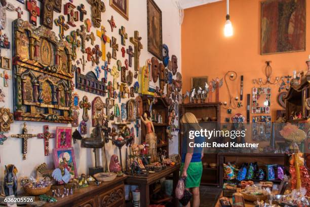 a woman tourist shops for souvenirs in a shop filled with hand made crafts in todos santos, mexico. - todos santos stockfoto's en -beelden