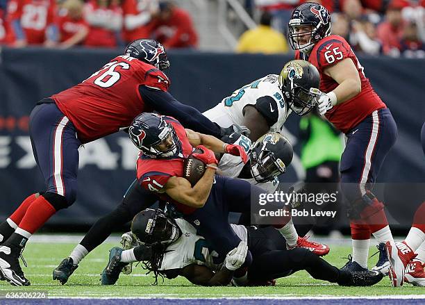 Jonathan Grimes of the Houston Texans is tackled by Telvin Smith of the Jacksonville Jaguars and Johnathan Cyprien as Duane Brown and Greg Mancz...