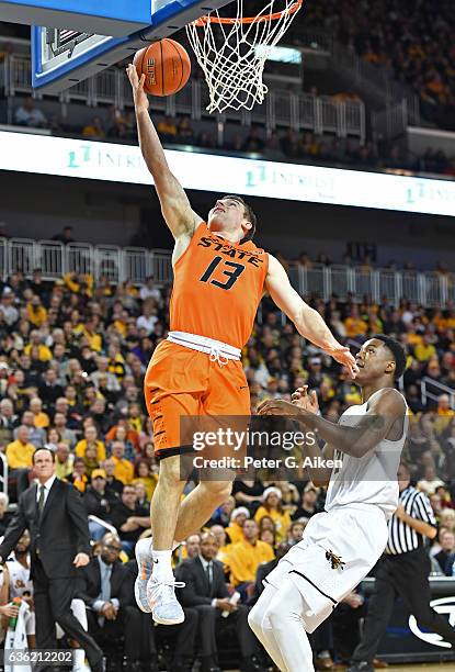 Guard Phil Forte III of the Oklahoma State Cowboys drives to the basket for a lay up against forward Darral Willis Jr. #21 of the Wichita State...