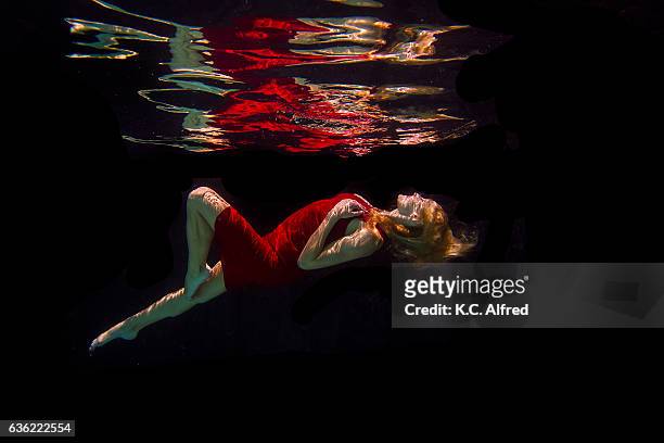 portrait of a female model underwater in a swimming pool with a black background in san diego, california. - long skinny legs ストックフォトと画像