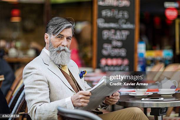 senior businessman with newspaper at street cafe - frans terras stockfoto's en -beelden