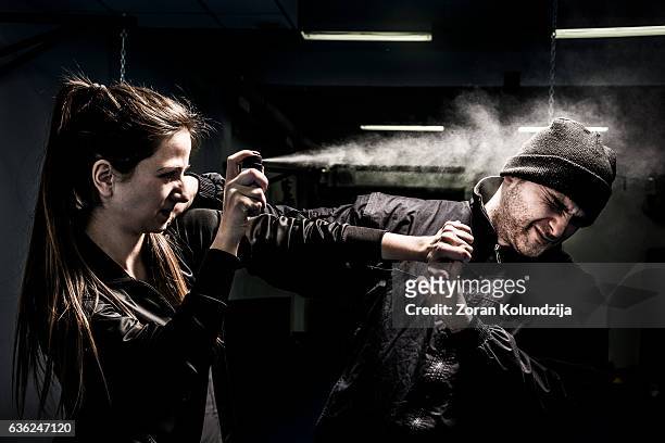 woman using pepper spray for self defense against attacker - self defense stockfoto's en -beelden