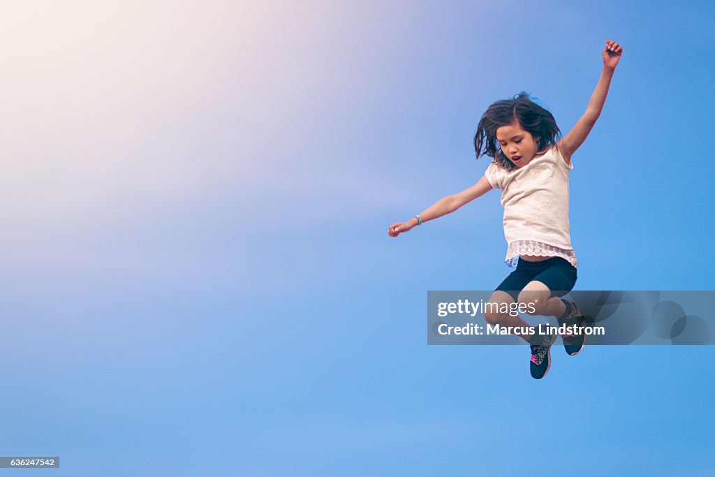 Niña saltando hacia el cielo