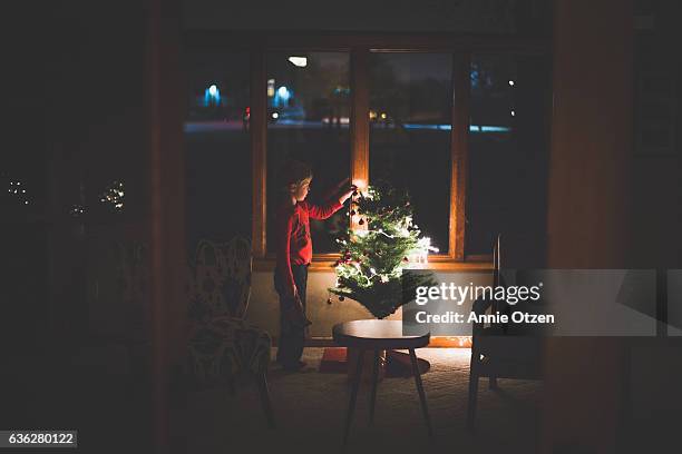 little boy decorating christmas tree - christmas dark stockfoto's en -beelden