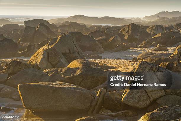 sunset in the sea with a group of big rocks and two people walking in the rocks. dreamlike  twilight. a guarda. galicia - guarda sol stock pictures, royalty-free photos & images