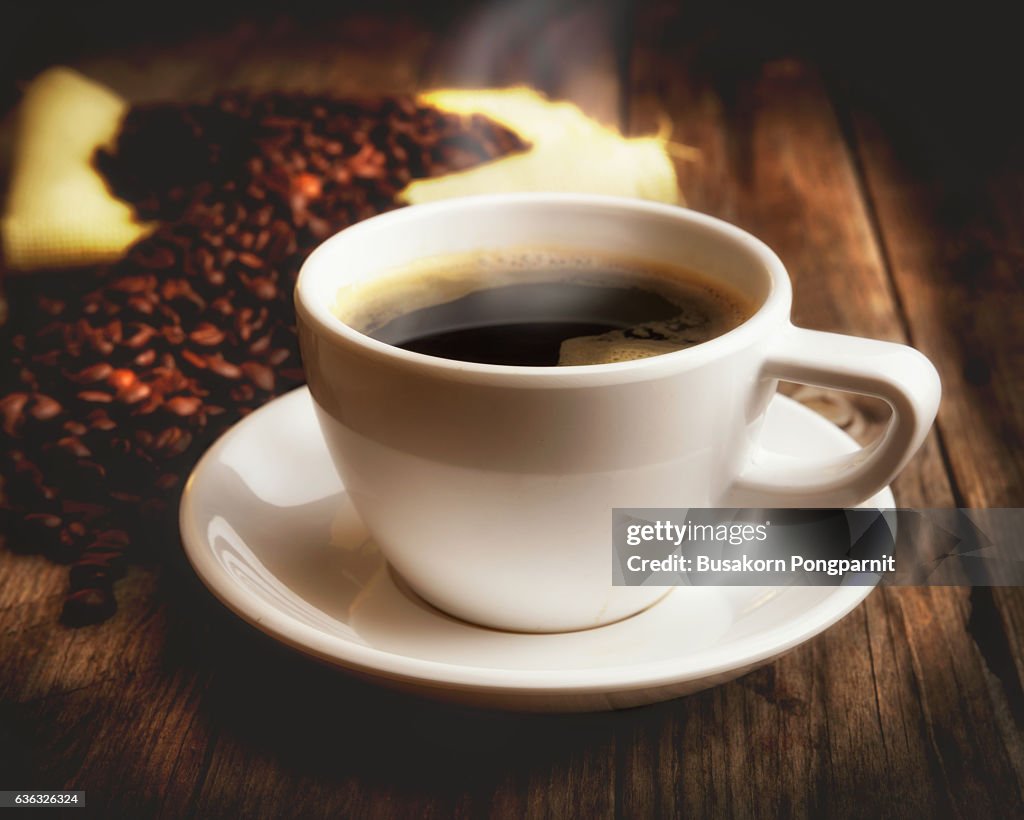 Cup of coffee and coffee beans over dark background