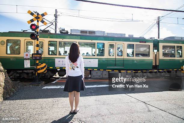 girl waiting and looking at train passing - kamakura stock pictures, royalty-free photos & images