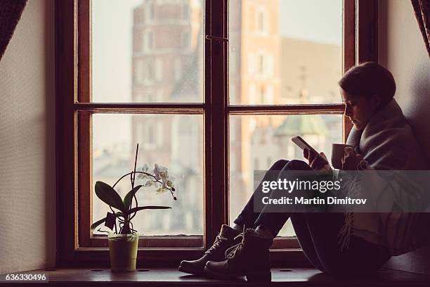 woman on the window texting - winter sadness stock pictures, royalty-free photos & images