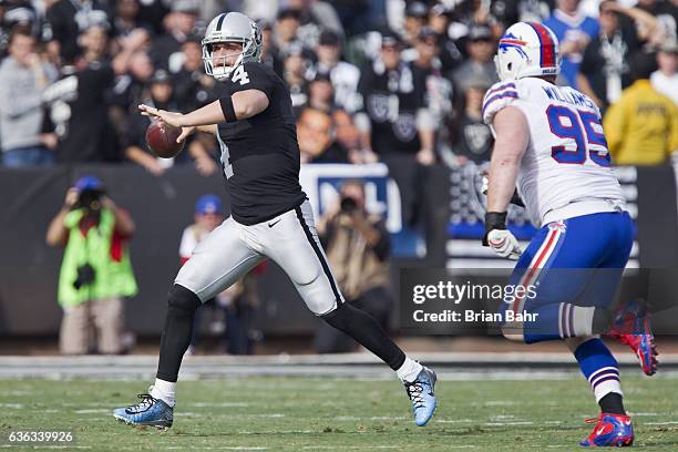 Quarterback Derek Carr of the Oakland Raiders rolls out to throw against defensive end Jerel Worthy of the Buffalo Bills in the first quarter on...