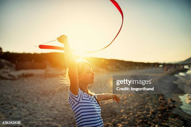 kleines mädchen, das gymnastik am strand macht. - ribbon dance stock-fotos und bilder