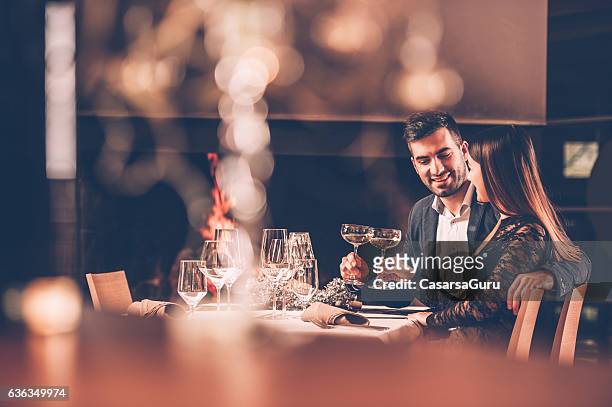young couple enjoying a romantic dinner together - date night stock pictures, royalty-free photos & images
