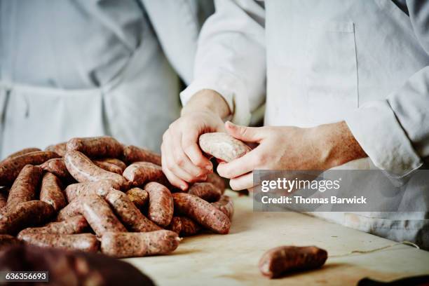 butcher preparing sausage links at workbench - butcher stockfoto's en -beelden