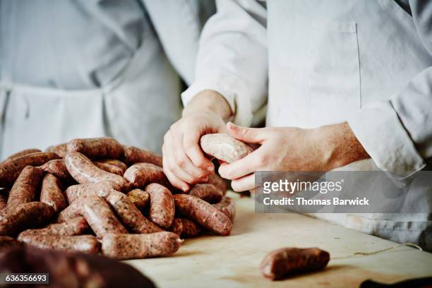butcher preparing sausage links at workbench - slaktare bildbanksfoton och bilder