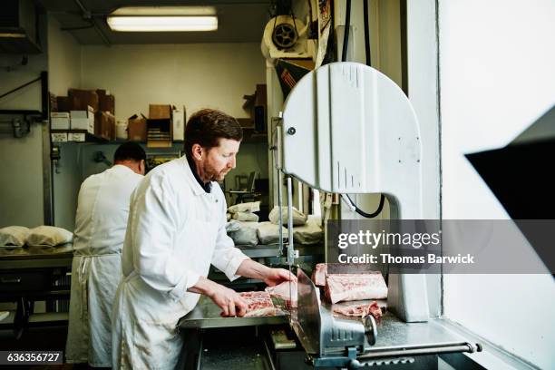 owner of butcher shop making cuts at band saw - meat factory stock pictures, royalty-free photos & images