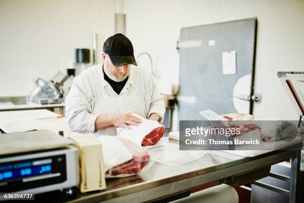 butcher packaging orders for customers at counter - boucher photos et images de collection