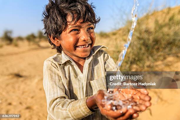 indian little boy drinking fresh water, desert village, rajasthan, india - boy indian stockfoto's en -beelden