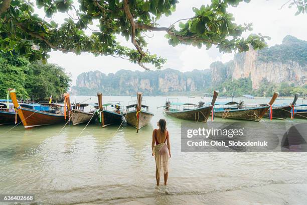 mujer cerca de los barcos en la playa en tailandia - krabi fotografías e imágenes de stock
