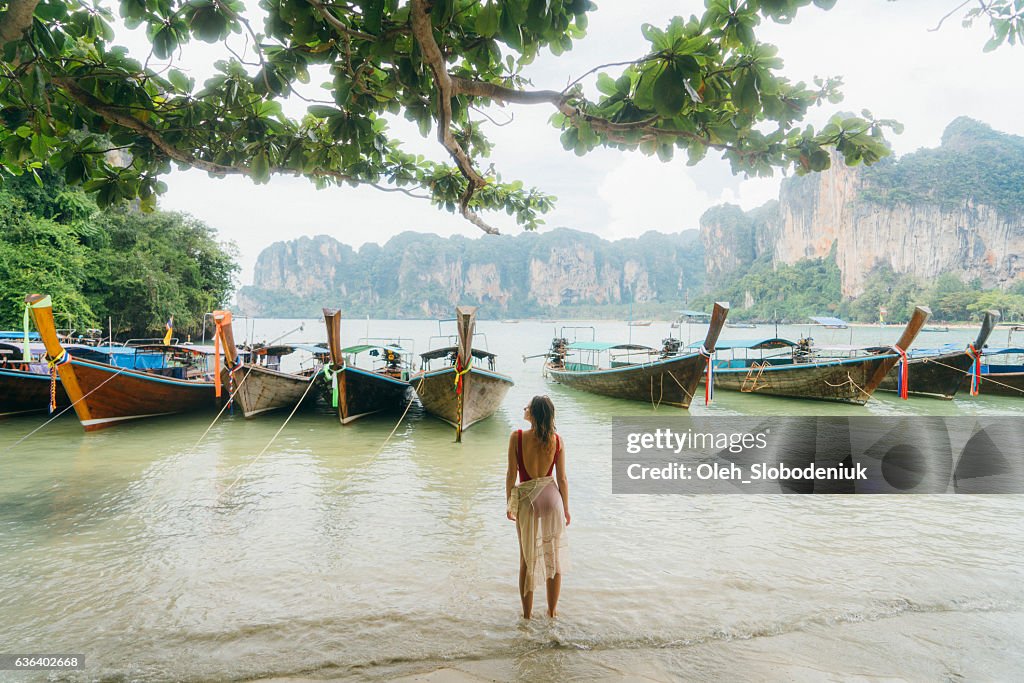 Woman near the boats on beach in Thailand