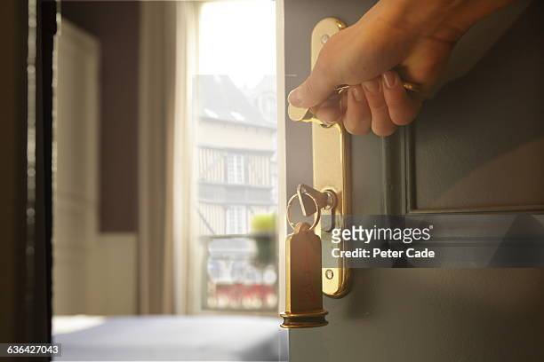 hand opening hotel room door, view through balcony - deur stockfoto's en -beelden