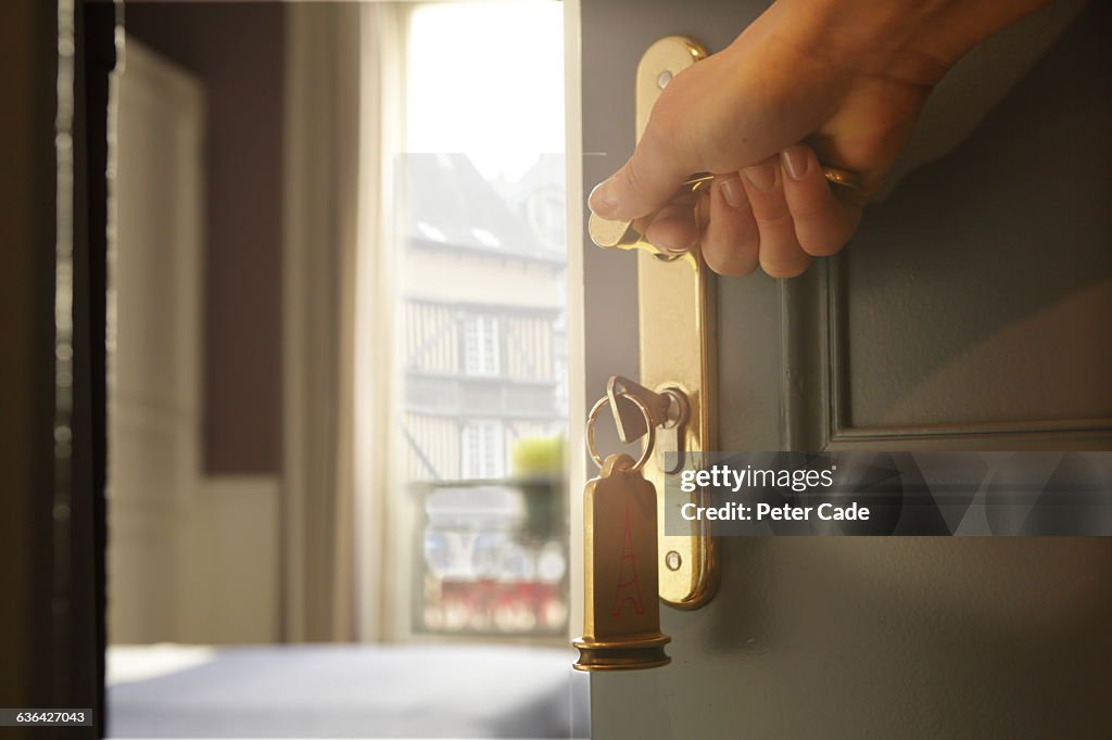 Hand opening hotel room door, view through balcony