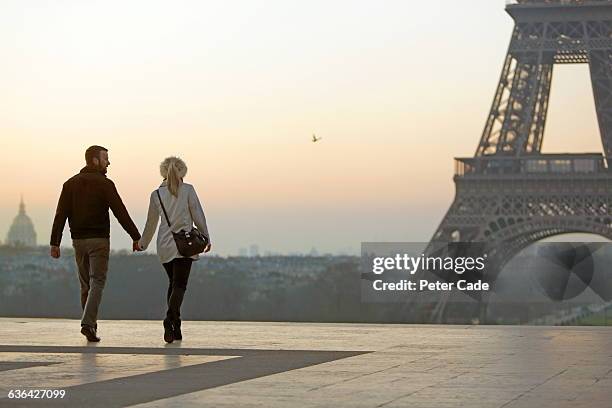 couple holding hands, view of eiffel tower - trench coat back stock pictures, royalty-free photos & images