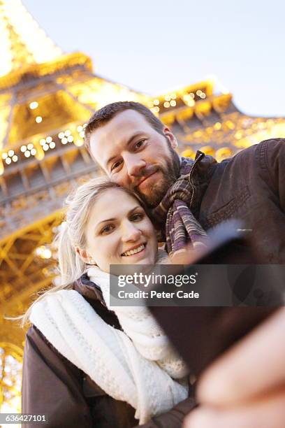 couple taking photo next to eiffel tower - couple paris stockfoto's en -beelden