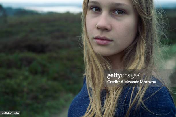 a girl looks at the camera on a background of a green meadow - blue lips stock pictures, royalty-free photos & images