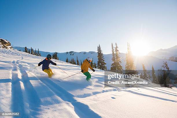 couple skiing on a sunny powder day - 40s couple sunny stockfoto's en -beelden