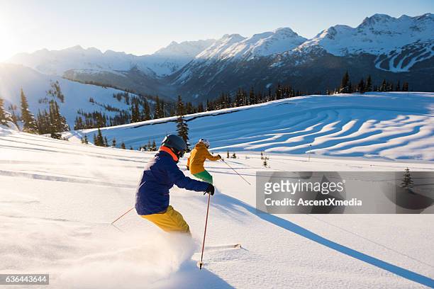 couple skiing on a sunny powder day - 40s couple sunny stockfoto's en -beelden