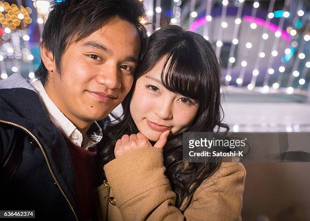 pareja joven tomando foto selfie en luces de navidad - autorretratarse fotografías e imágenes de stock