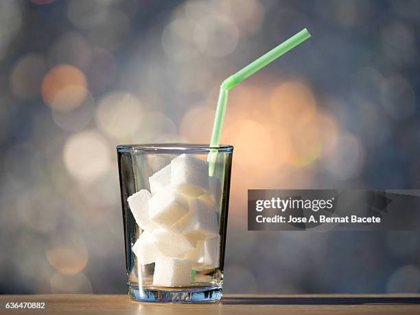 glass of crystal with a straw  and heap of sugar cubes , it is the equivalent in sugar to a drink of refreshment sweetened - excess sugar stock pictures, royalty-free photos & images