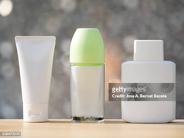 blank cosmetics containers,  after shave ,facial cream   and deodorant,   illuminated by sunlight - aftershave bottle stock-fotos und bilder
