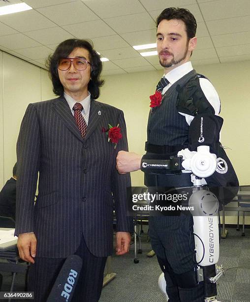 Japan - Yoshiyuki Sankai , president of Cyberdyne Inc., and a model wearing the company's HAL robot suit, pose for photos at the Tokyo Stock Exchange...