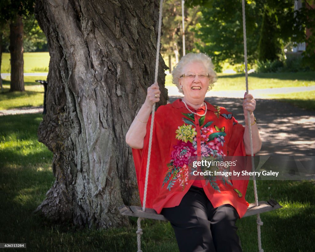 Woman over 80 swinging happily on a swing