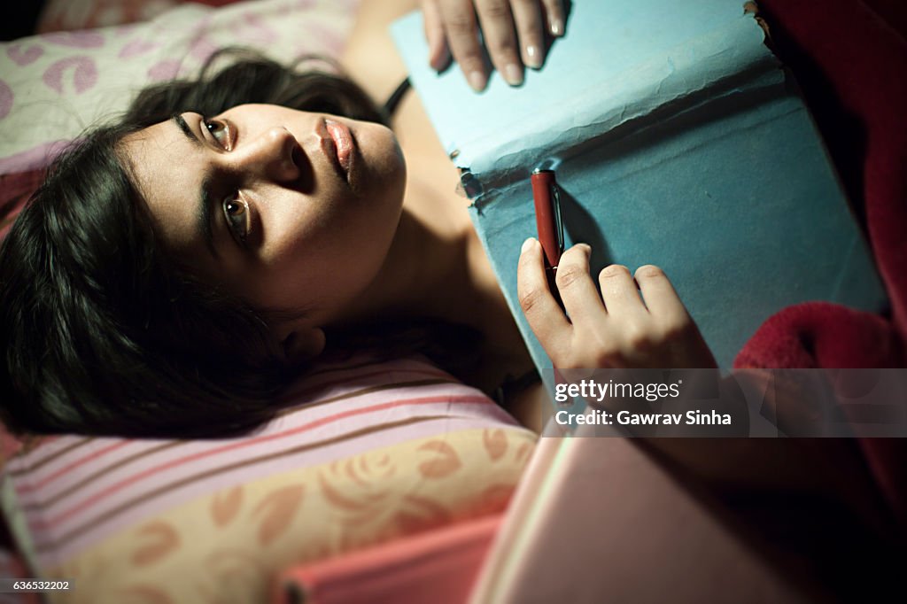 Asian serene girl thinking and lying on bed with book.