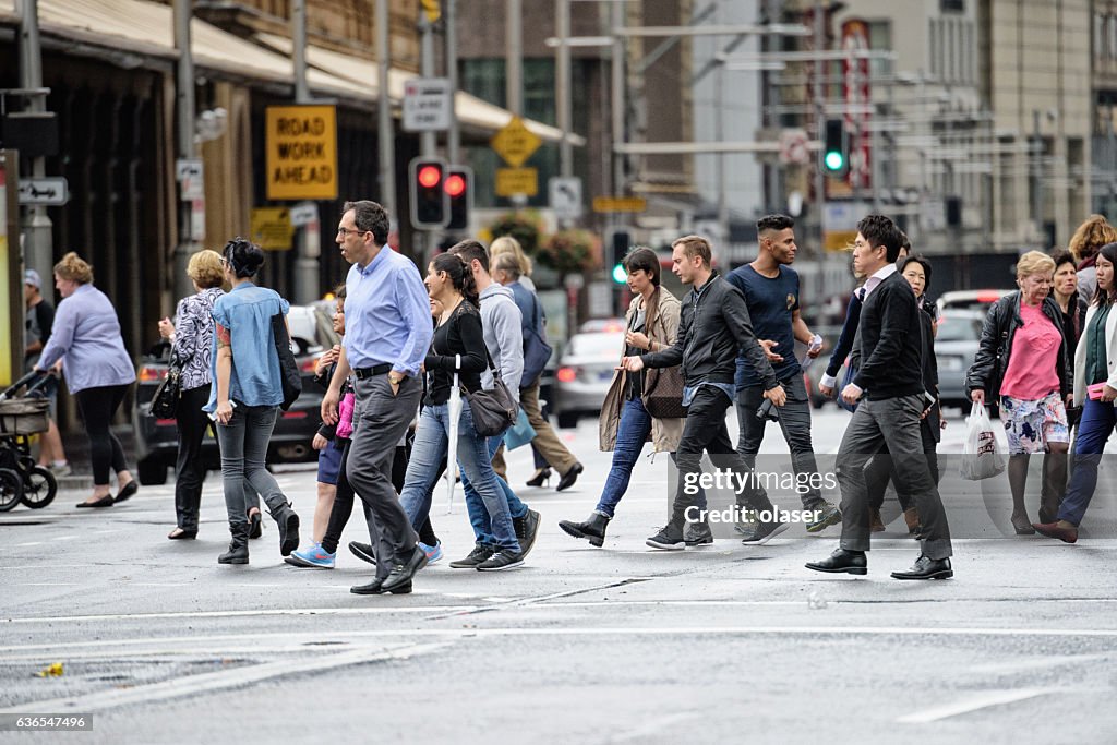 Diversified people crowd crossing rain wet street