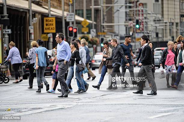 diversified people crowd crossing rain wet street - pedestrian stock pictures, royalty-free photos & images