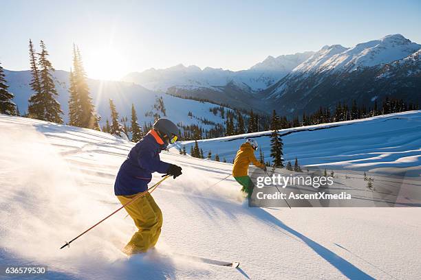 couple skiing on a sunny powder day - estância de esqui imagens e fotografias de stock