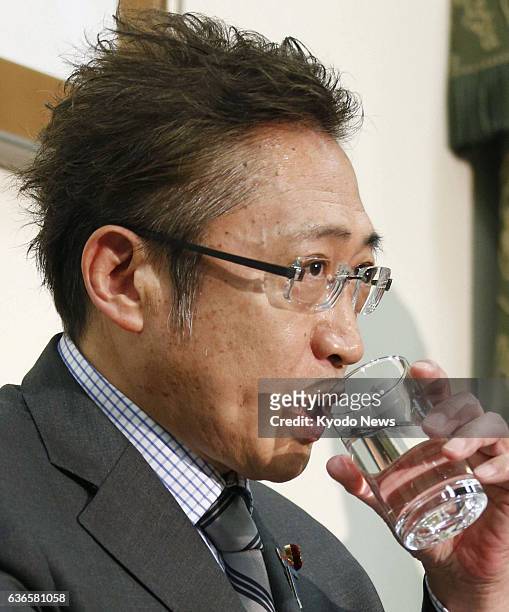 Japan - Your Party leader Yoshimi Watanabe drinks water during a press conference at the Diet building in Tokyo on April 7 held to announce he will...