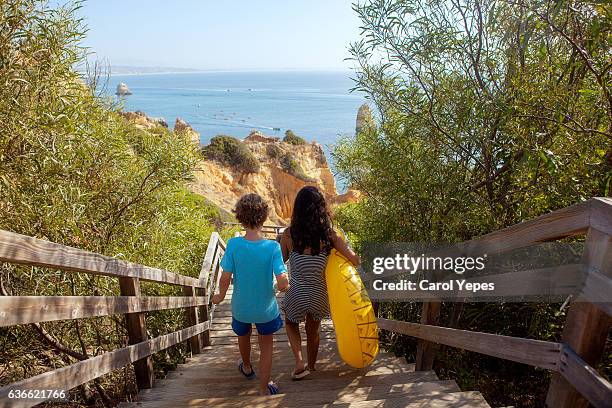 two kids walking down to beach.rear view - distrito de faro portugal fotografías e imágenes de stock