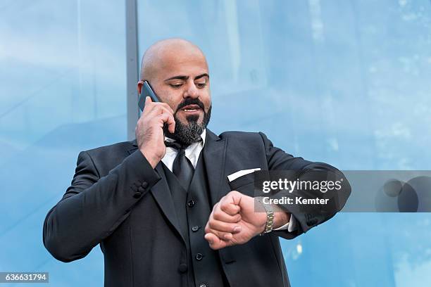 uomo d'affari calvo con barba nera parlando allo smartphone - mezzo busto foto e immagini stock