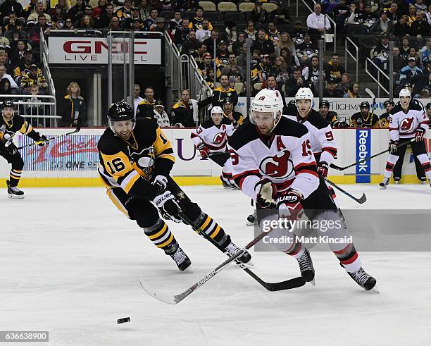 Travis Zajec of the New Jersey Devils reaches for the puck against Eric Fehr the Pittsburgh Penguins at PPG PAINTS Arena on December 23, 2016 in...