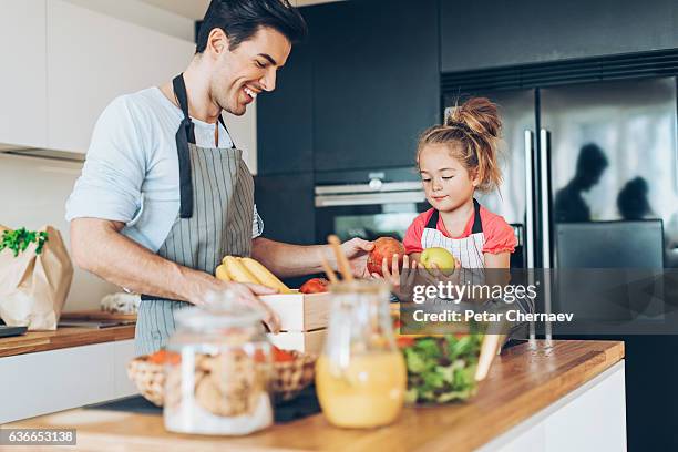 vater und tochter sortieren frisches obst - young man groceries kitchen stock-fotos und bilder