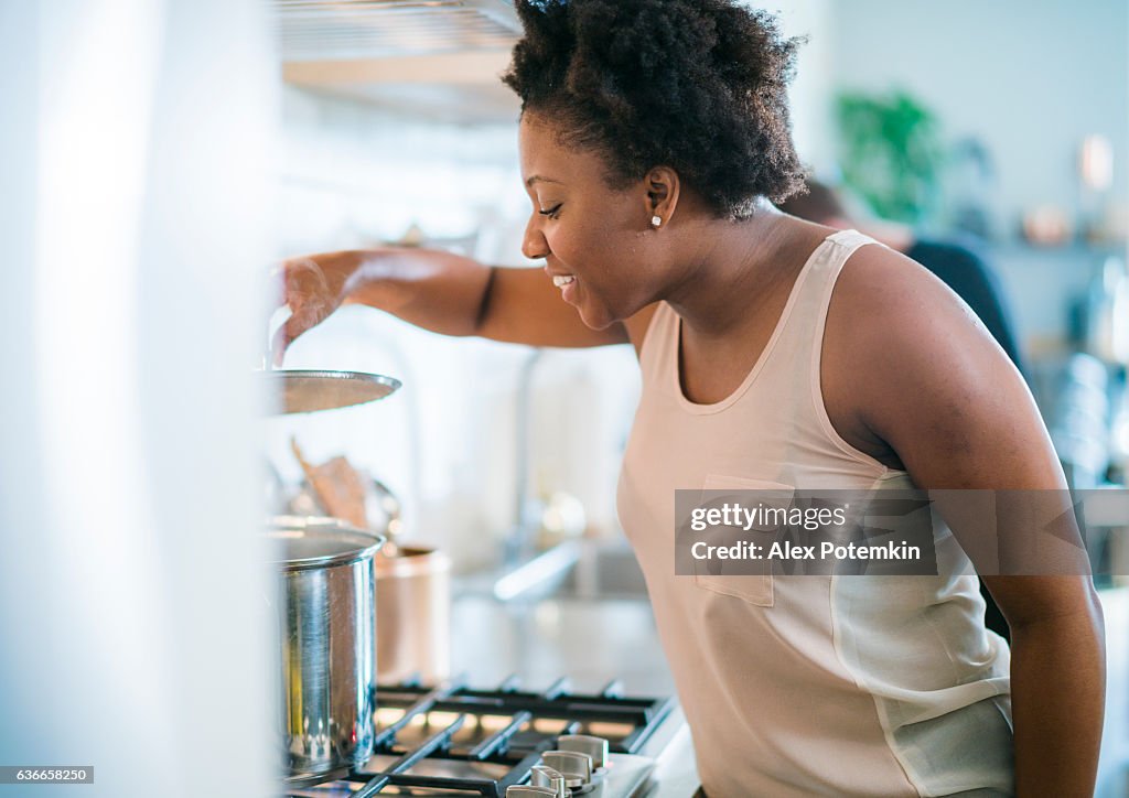 Young pretty black woman make soup in kitchen