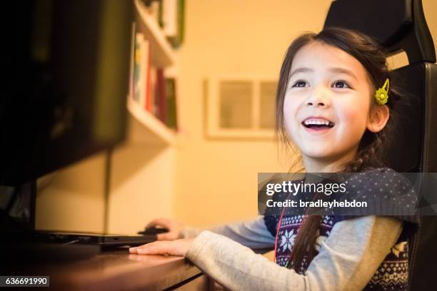 glückliches kleines mädchen mit spaß mit einem computer zu hause - eurasische herkunft stock-fotos und bilder