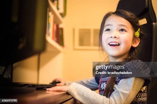 happy little girl having fun using a computer at home - cute little asian girls 個照片及圖片檔