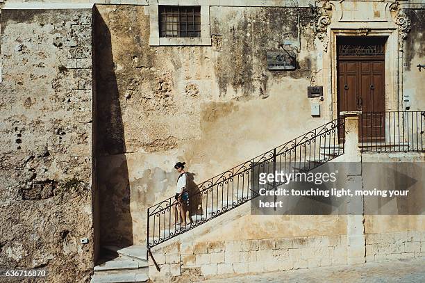 travel like a local - young female tourist walking down steps in front of an old building in unesco city noto, sicily, italy - noto fotografías e imágenes de stock